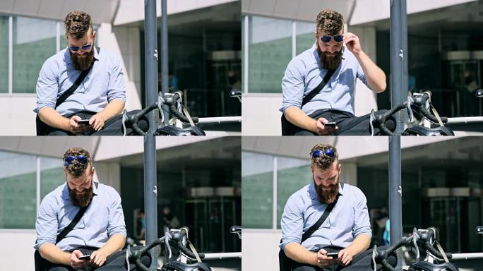 带胡须的DS商人在办公楼前使用智能手机