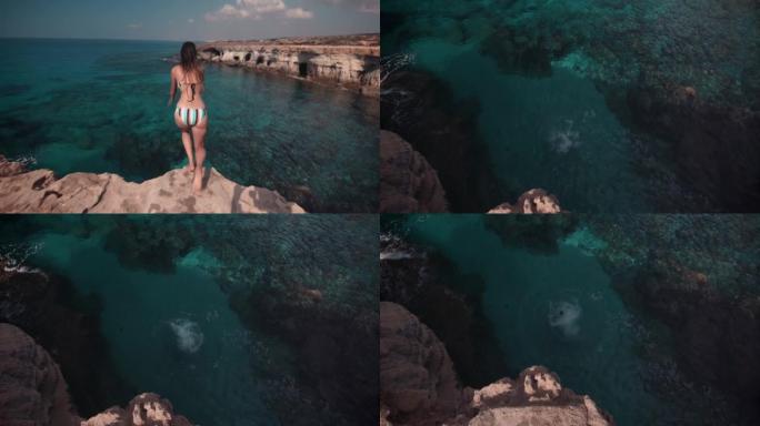 年轻女子从岩石悬崖跳入海洋