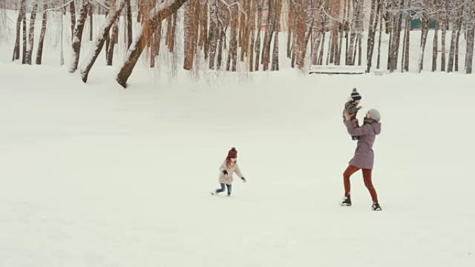 年轻的母亲和她的孩子在雪地里玩耍和玩耍