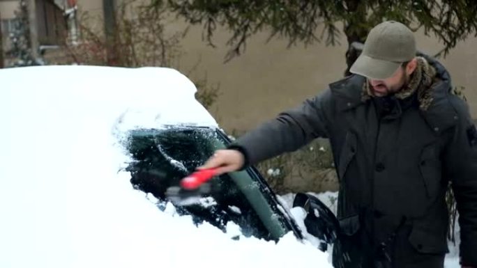 男子从汽车上除雪