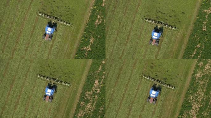 空中: 在拖拉机上飞来飞去tedding用耙子在农田上割草
