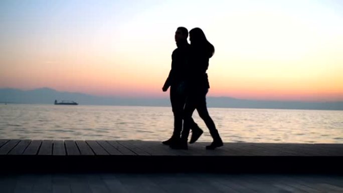 日落时分在海边散步的年轻夫妇
