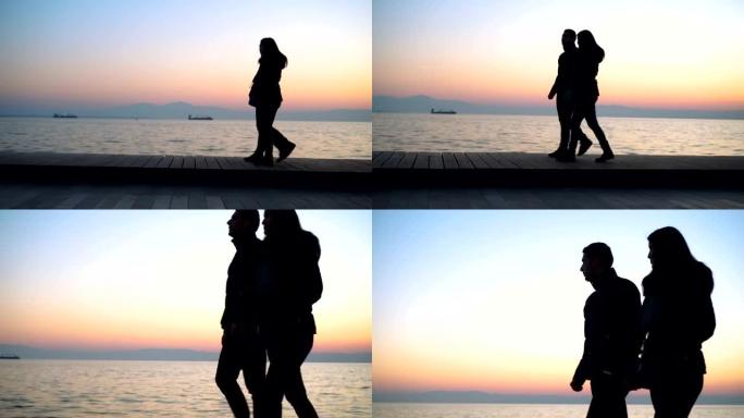 日落时分在海边散步的年轻夫妇