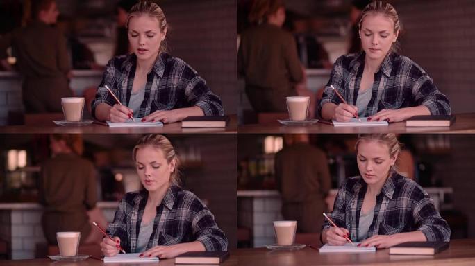 年轻女子在笔记本上画画，在咖啡馆喝咖啡