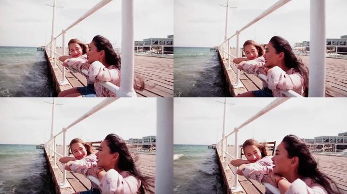 女性最好的朋友坐在码头上享受海风