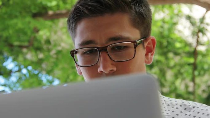 年轻的潮男学生在学校学习时使用笔记本电脑