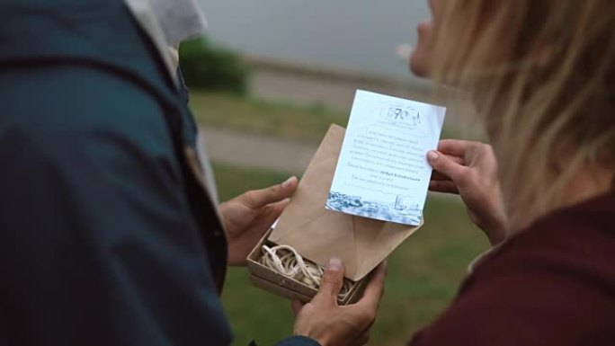 年轻迷人夫妇的特写镜头打开盒子，从信封中取出卡片并阅读
