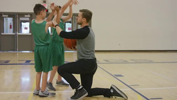 篮球教练向男孩展示适当的投篮技术