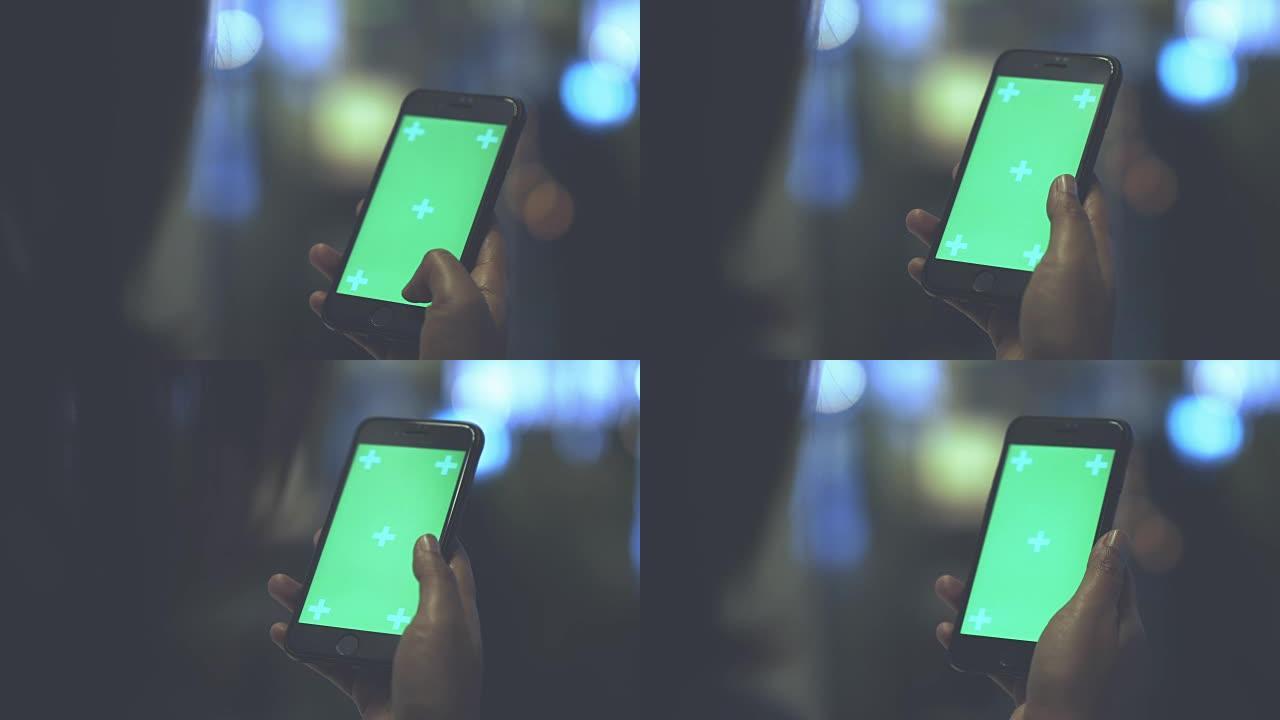 年轻女孩拿着绿色屏幕的智能手机