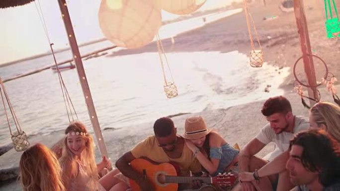 夏季海滩派对上年轻的多民族时髦朋友用吉他