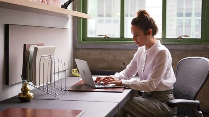 女人在办公室阅读文档并使用笔记本电脑，关闭