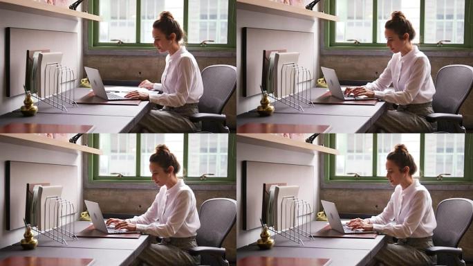 女人在办公室阅读文档并使用笔记本电脑，关闭