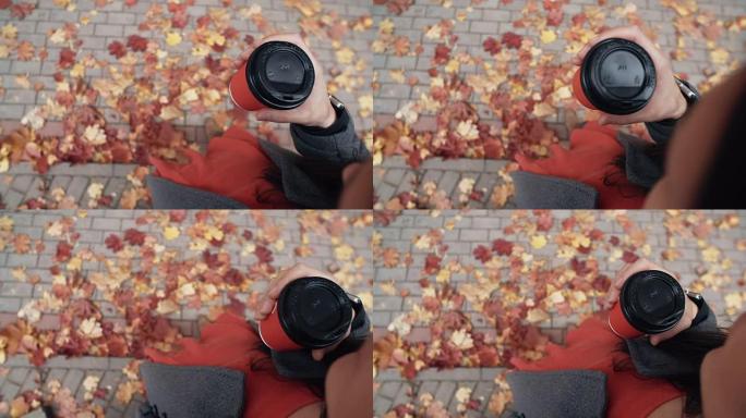 秋天。年轻时尚女人的俯视图，脚下拿着一杯咖啡，倒下的美丽枫叶全高清