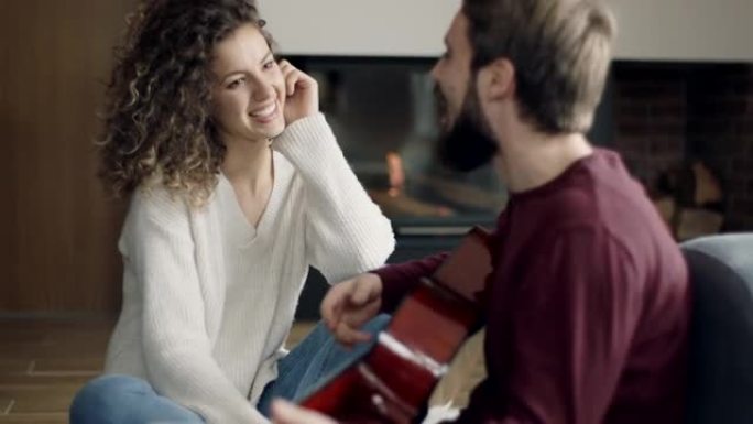 男人在家里的壁炉旁为女友弹吉他