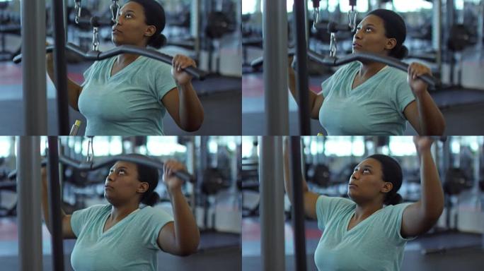 黑人妇女在健身房的下拉机器上锻炼