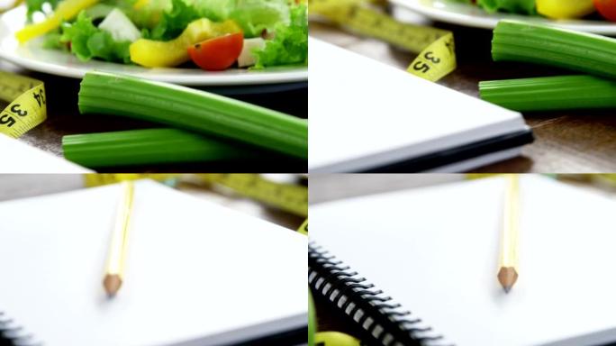 盘子里的蔬菜沙拉，桌子上有测量胶带和螺旋笔记本