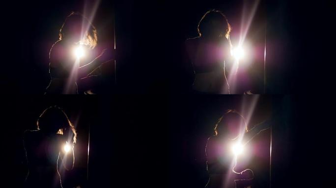 一个女孩在黑暗中用一台投影仪积极拳击的中拍。