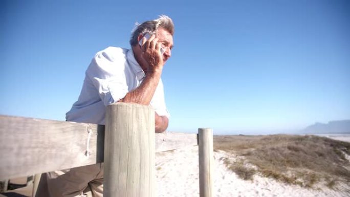 活跃的退休老人在海滩上打电话