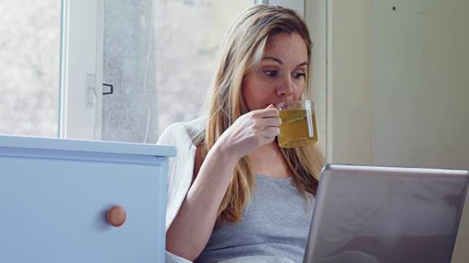 女人在喝绿茶时使用笔记本电脑4k