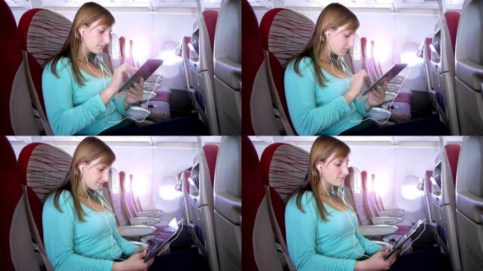 在飞机上使用数字平板电脑的年轻女子
