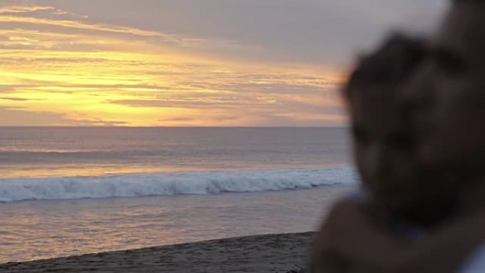 男人带着小女儿在日落时看着海洋