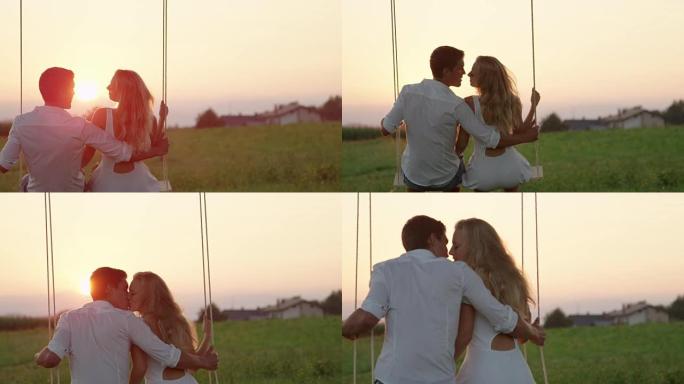 慢动作: 开朗的情侣在秋千上接吻，背景是浪漫的日落