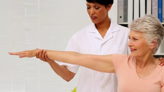 护士向老年患者展示如何锻炼受伤的手臂