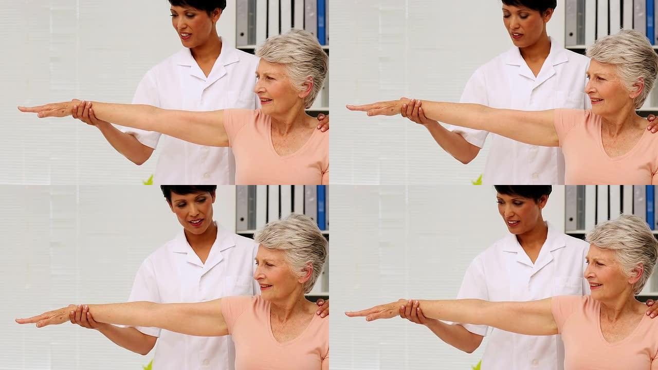护士向老年患者展示如何锻炼受伤的手臂