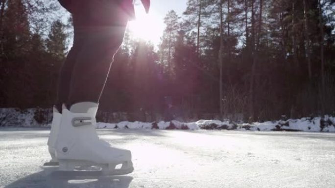 慢动作特写: 年轻的滑冰运动员在冰冻的池塘上旋转