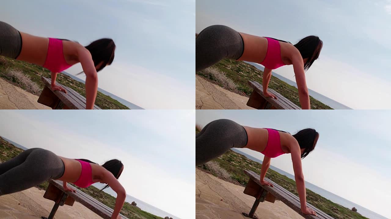 健康的女人在海边的长凳上做俯卧撑