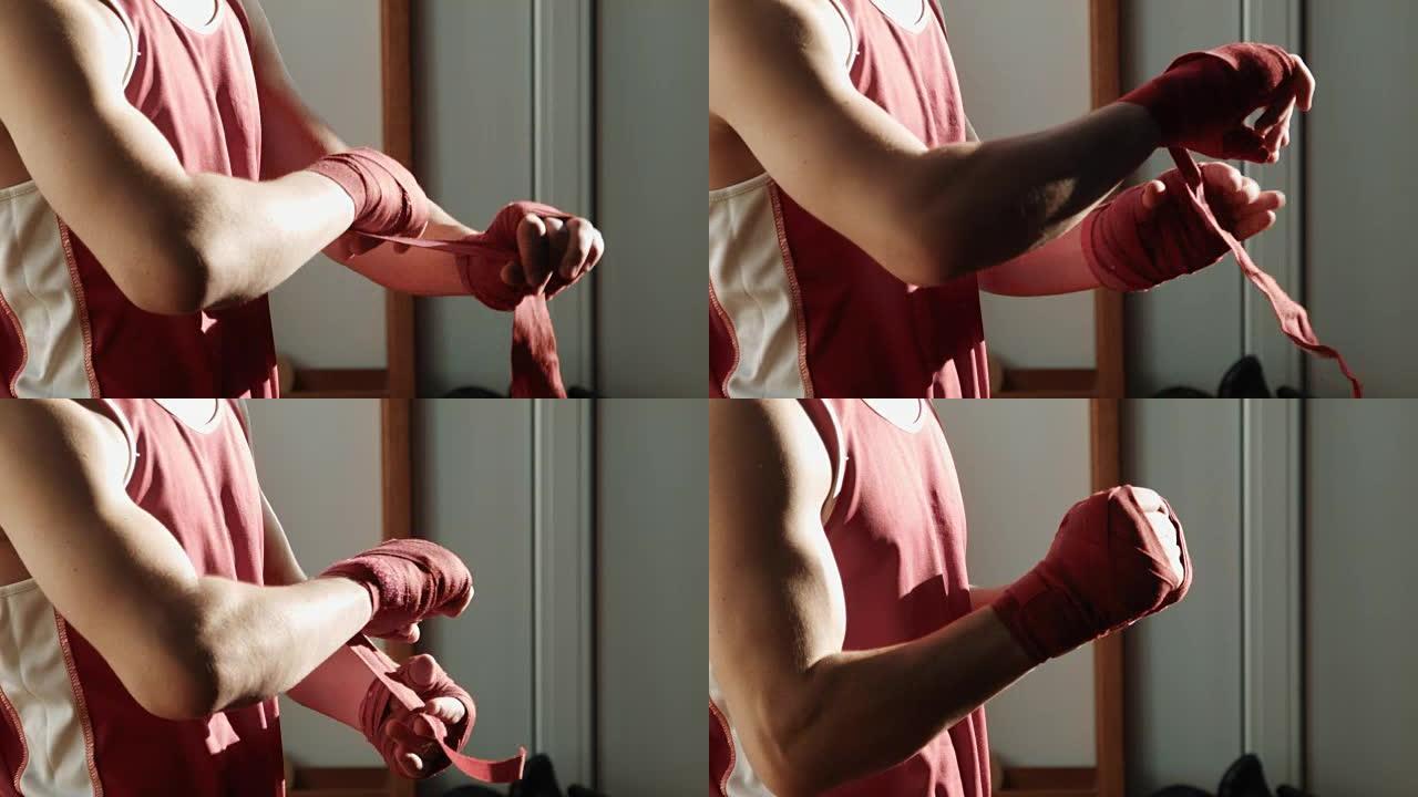 年轻的拳击手在手上拉着红色绷带并开始拳击