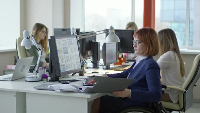 坐在轮椅上的截瘫女商人在办公室的办公桌上工作
