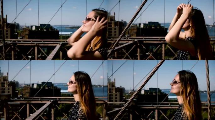 相机跟随美丽快乐的欧洲女孩穿着复古太阳镜，金色头发沿着布鲁克林大桥4K