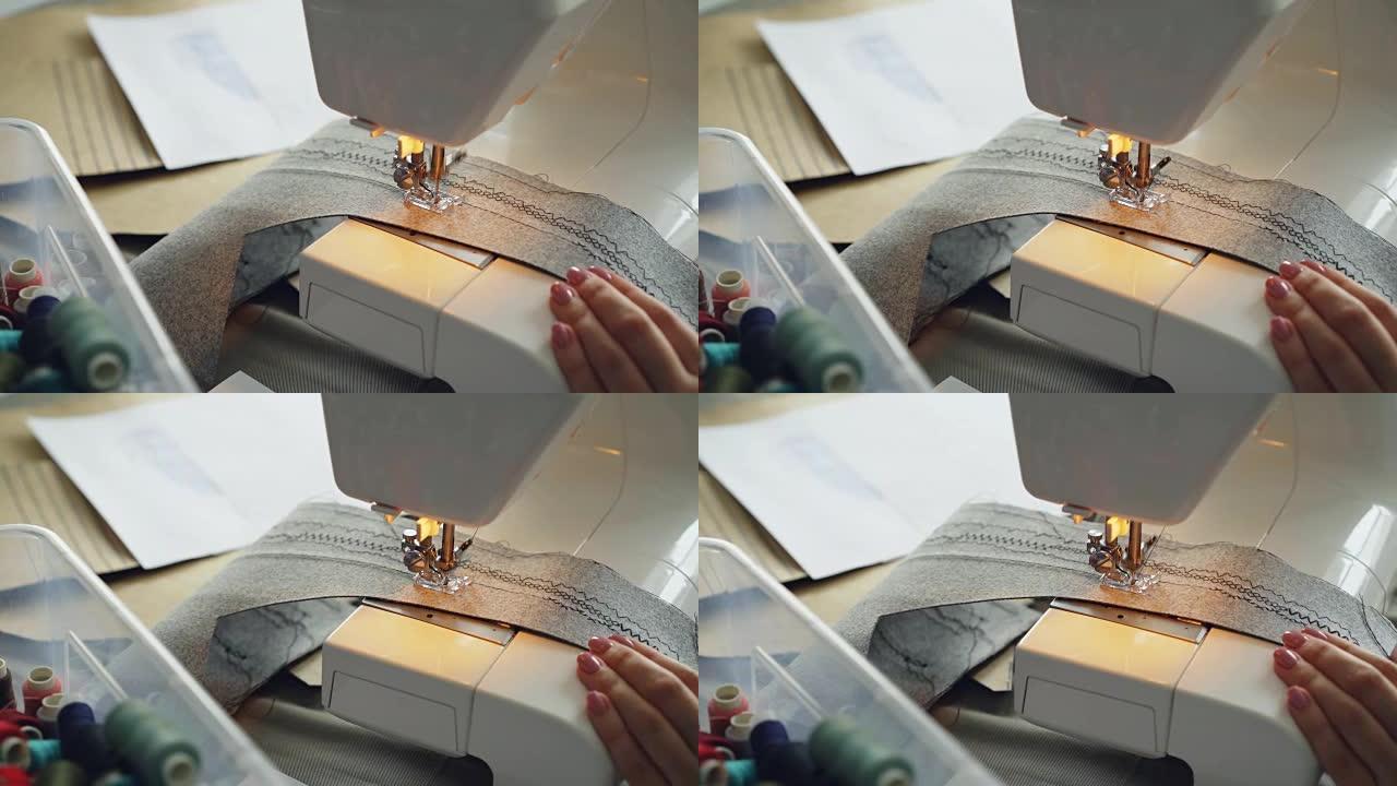 现代电动缝纫机拼接纺织品的特写镜头。女孩修剪整齐的手和五颜六色的缝纫线可见。