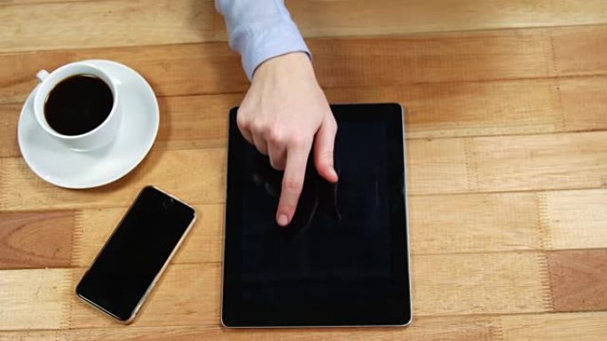 女商人在桌子上使用数字平板电脑，桌上放着一杯咖啡和手机