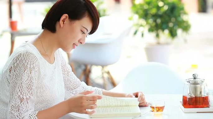 年轻年轻的亚洲女性在咖啡馆看书