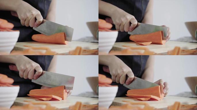 首席女士制作沙拉健康食品和在厨房切菜板上切碎胡萝卜的特写镜头。