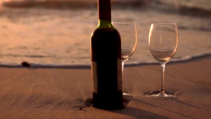 沙滩上的红酒瓶和玻璃杯