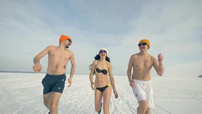 三个运动朋友在冬天穿着泳衣和太阳镜跑步。