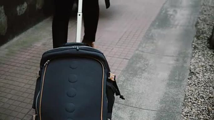 这位带着手提箱的年轻女子的特写镜头穿过街道，到达新城市并前往酒店