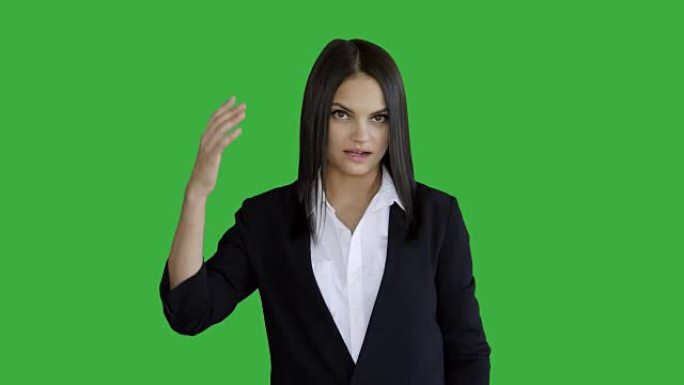 年轻迷人的黑发女人站在绿色屏幕背景下孤立。穿着西装的美丽职业女性肖像