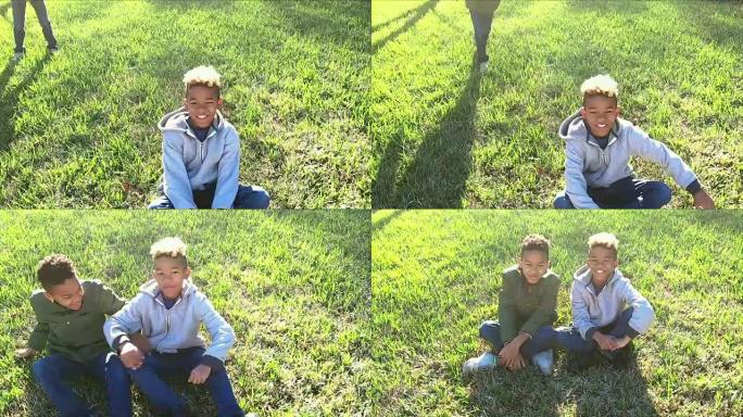 一个男孩与顽皮的兄弟一起，盘腿坐在草地上