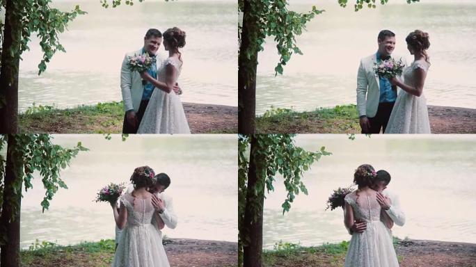 相爱的幸福夫妇分享他们的婚礼。他们站在河岸上，有说有笑。漂亮的服装，花束