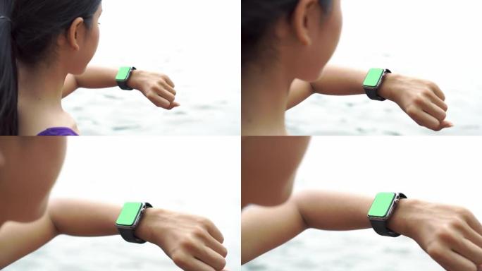 女人在智能手表上慢跑和检查脉搏，绿屏。