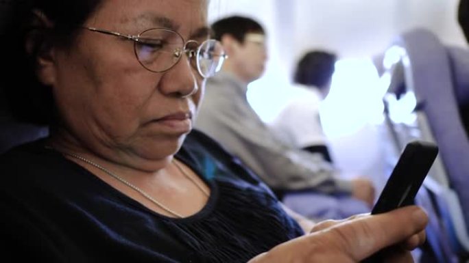 高级女性在飞机上使用智能手机上的wifi。