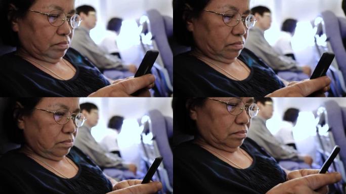 高级女性在飞机上使用智能手机上的wifi。