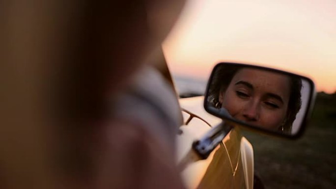 看日落的女人在汽车上的侧视镜反射