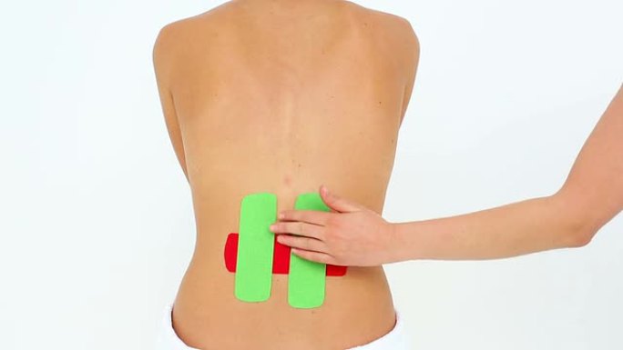 背部贴有红色和绿色kinesio胶带的女人