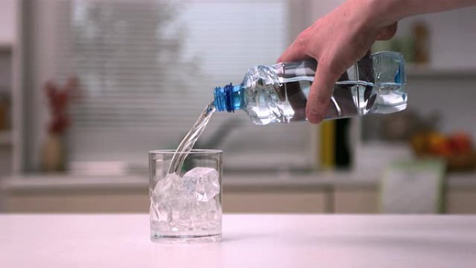 用手将水倒入装有冰块的玻璃杯中