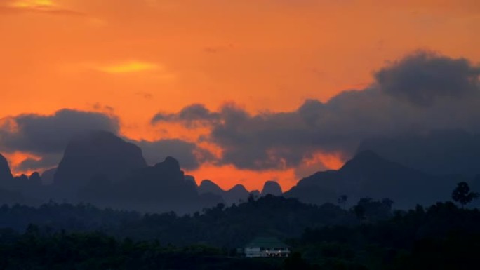 热带的橙色日落天空。黄昏时山脉的轮廓。泰国考索克国家公园。平移镜头